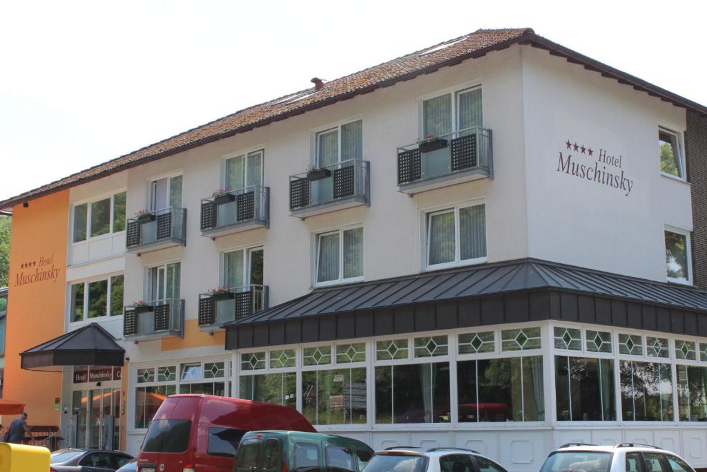 a building with cars parked in front of it at Hotel Muschinsky in Bad Lauterberg