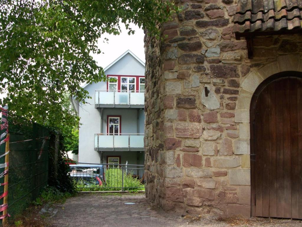 een wit huis met een balkon achter een stenen muur bij Ferienwohnungen "AM HELLGREVENHOF" in Eisenach