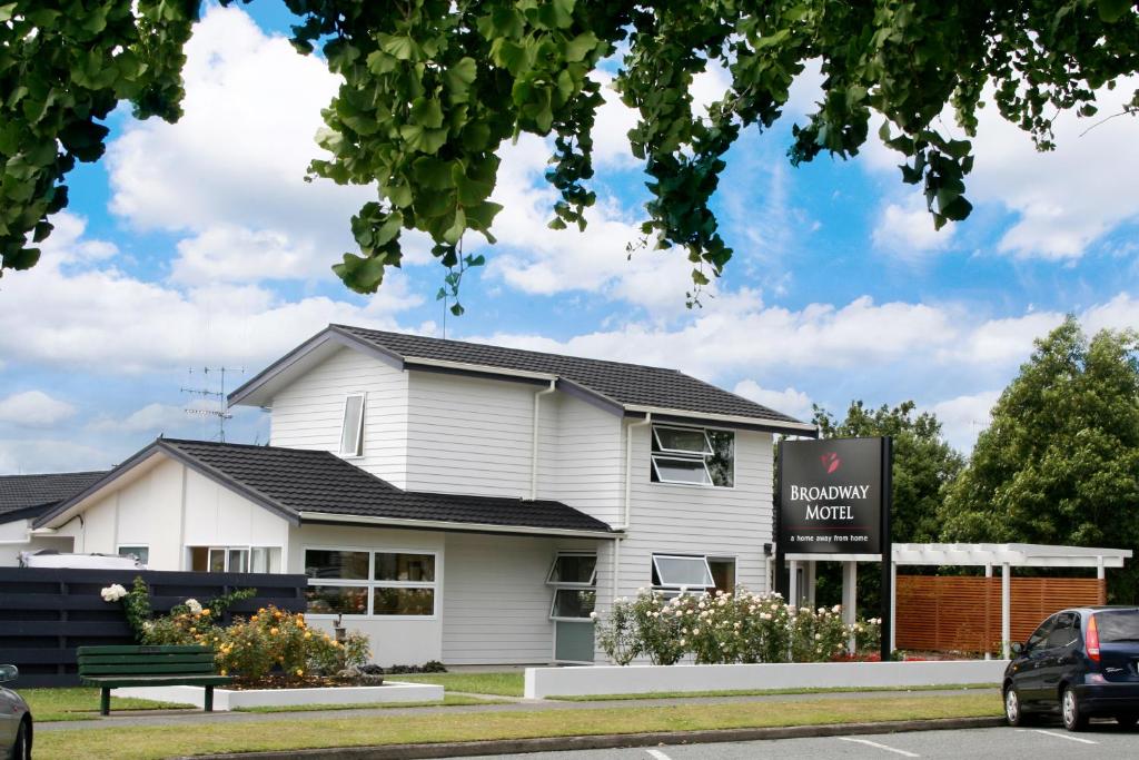 un edificio blanco con un banco delante en Broadway Motel & Miro Court Villas, en Matamata