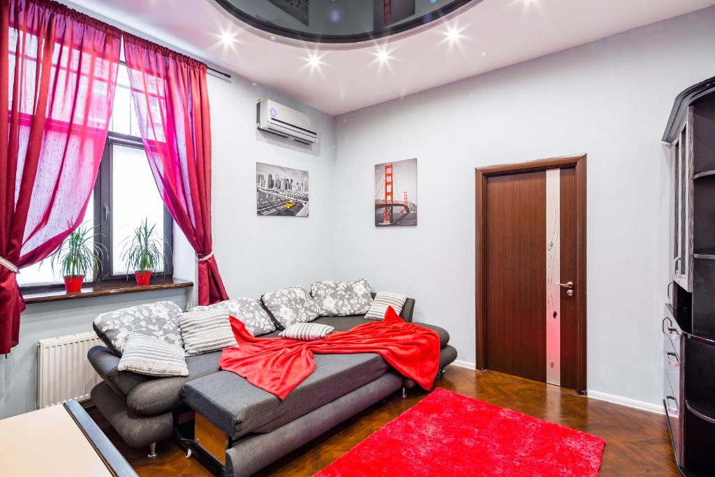 ein Wohnzimmer mit einem Sofa und einer roten Decke in der Unterkunft Alfa Apartments Uzhgorodska in Lwiw