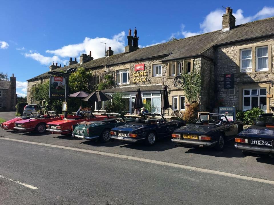 una fila de autos estacionados frente a un edificio en The Game Cock Inn, en Austwick