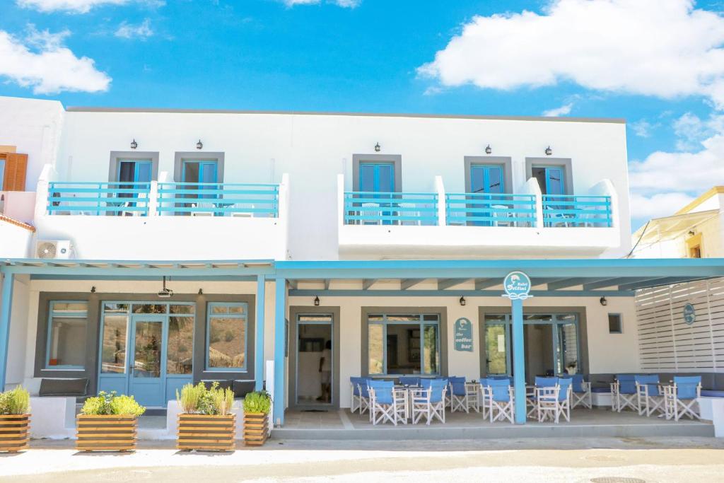 a white building with chairs and tables in front of it at Delfini Hotel in Skala