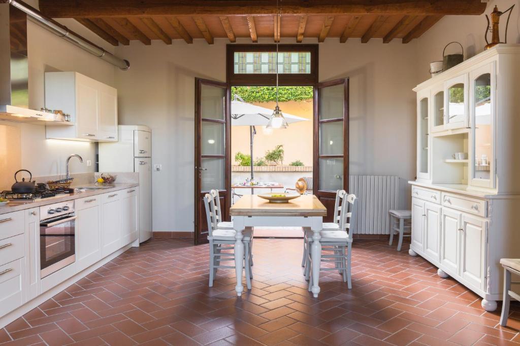 cocina con armarios blancos, mesa y sillas en Casa Valliprata, en Bucciano