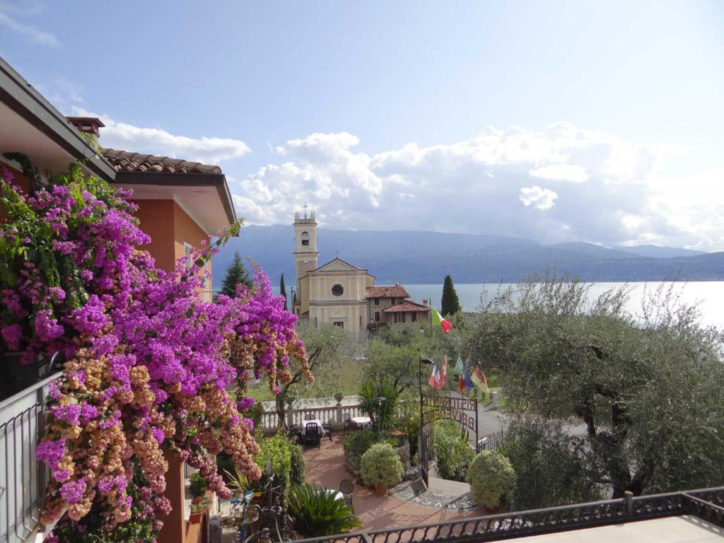 een balkon met uitzicht op een stad met paarse bloemen bij Belvedere Hotel & Villa in Toscolano Maderno