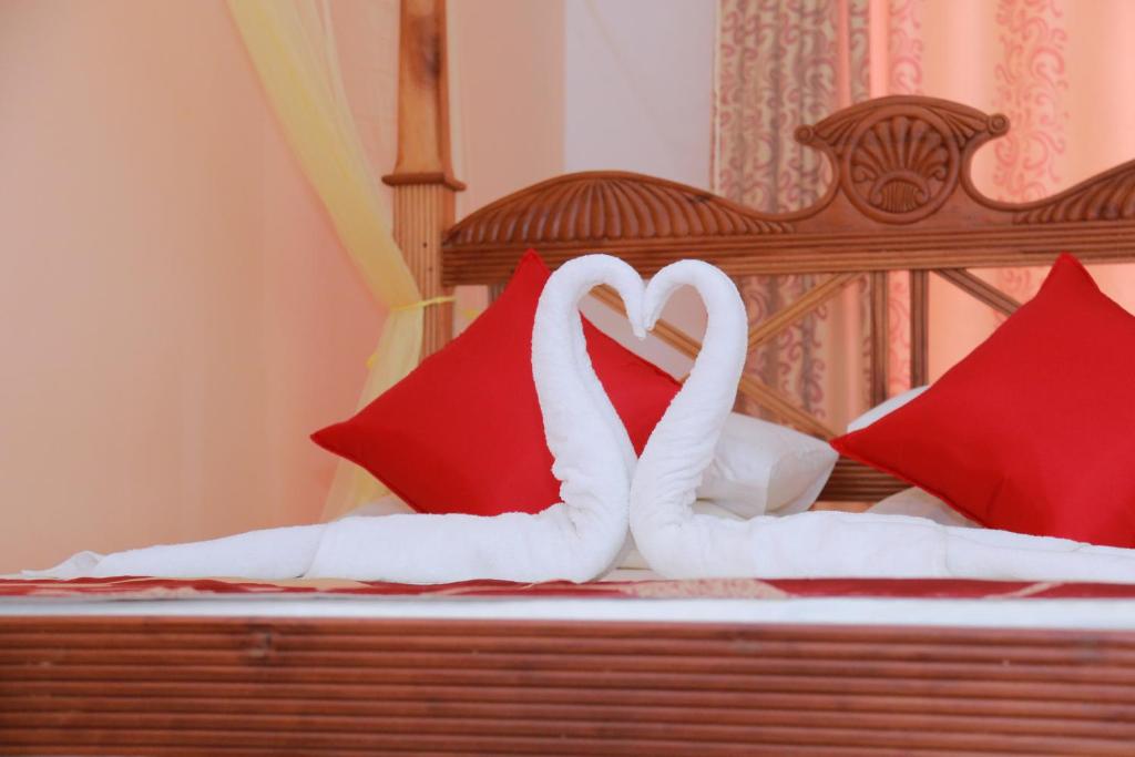 two white swans sitting on a bed with red pillows at Soma villa in Galle