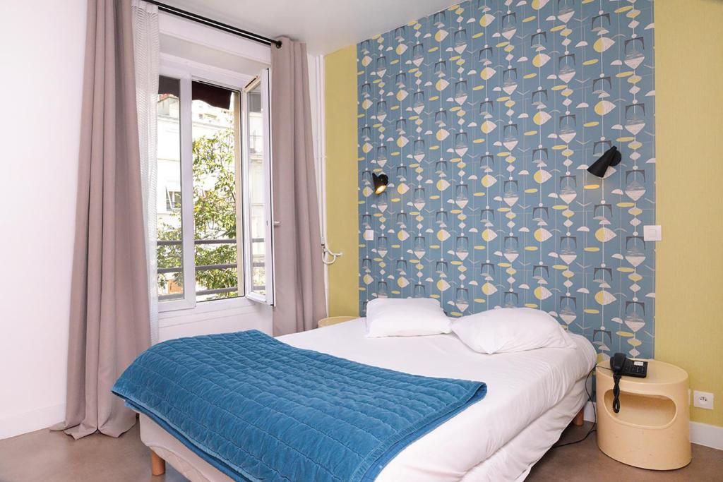 a bedroom with a bed with a blue wall at Zazie Hôtel in Paris