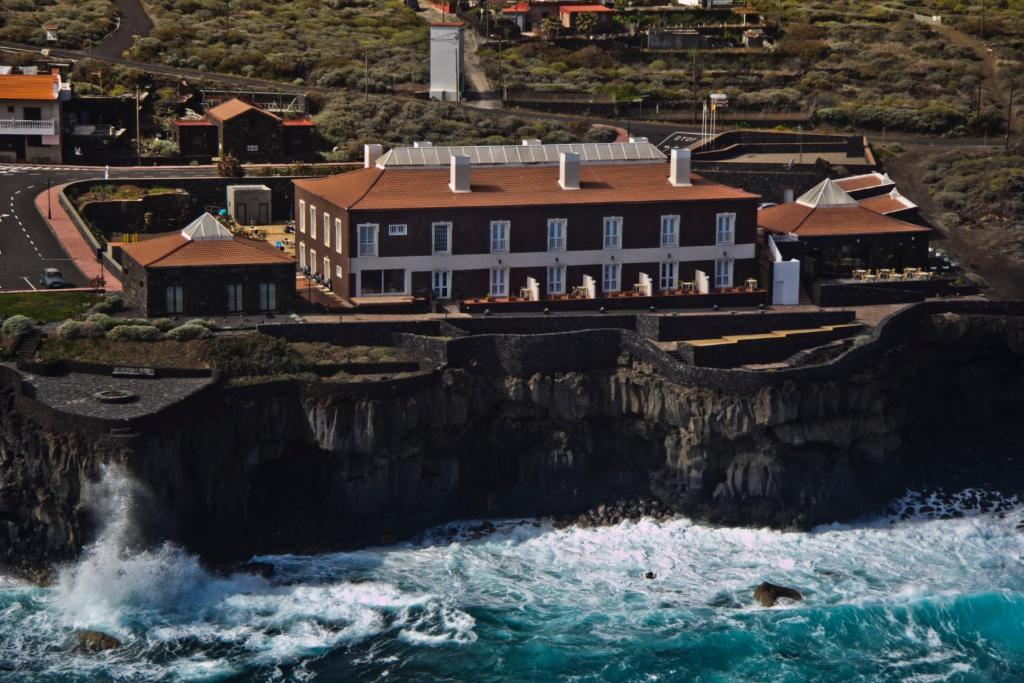 a building on a cliff next to the ocean at Balneario Pozo de la Salud in Sabinosa