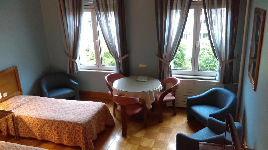 ストラスブールにあるホテル ドゥ ロランジェリーのベッド、テーブル、椅子が備わる客室です。
