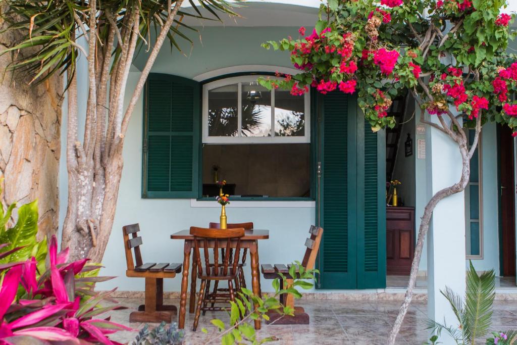 een patio met een tafel, stoelen en bloemen bij Americano's Suítes in Arraial do Cabo