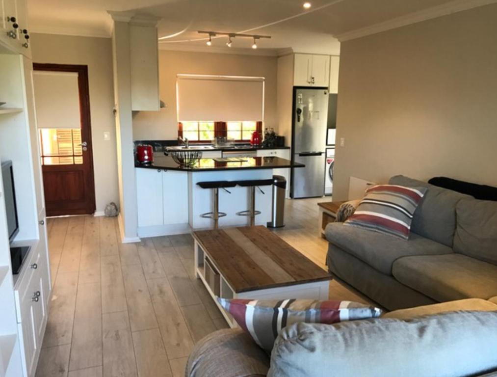 a living room with a couch and a kitchen at Whale Rock Gardens in Plettenberg Bay