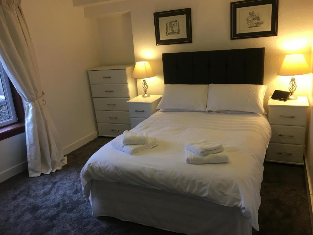 EllonにあるCosy One Bedroom Apartment - Ellon Town Centreのベッドルーム1室(白い大型ベッド1台、ナイトスタンド2台付)