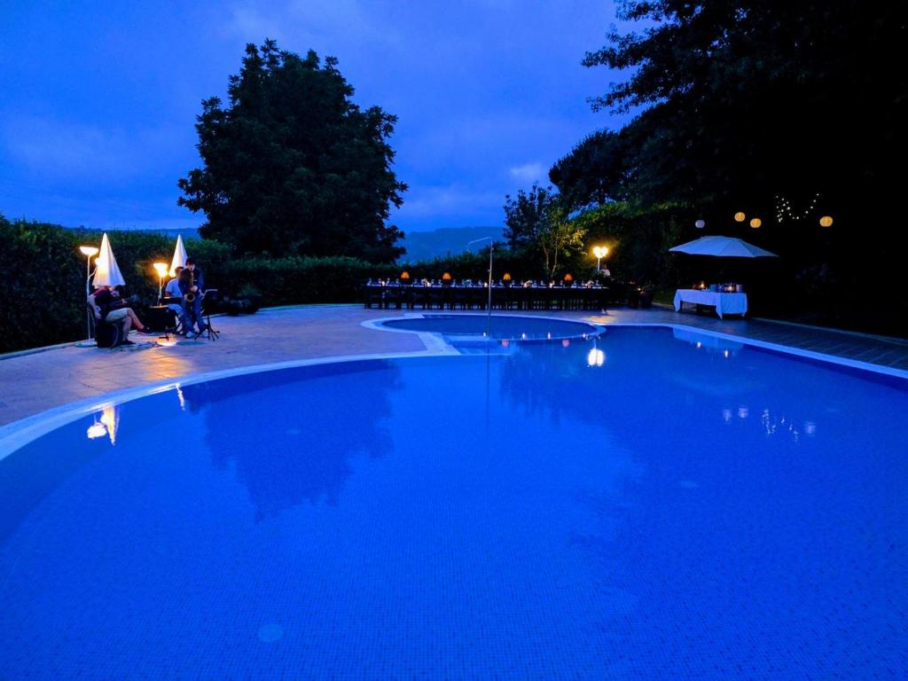 ein großer blauer Pool mit Menschen, die nachts um ihn herum sitzen in der Unterkunft Casa do Almocreve in Baião