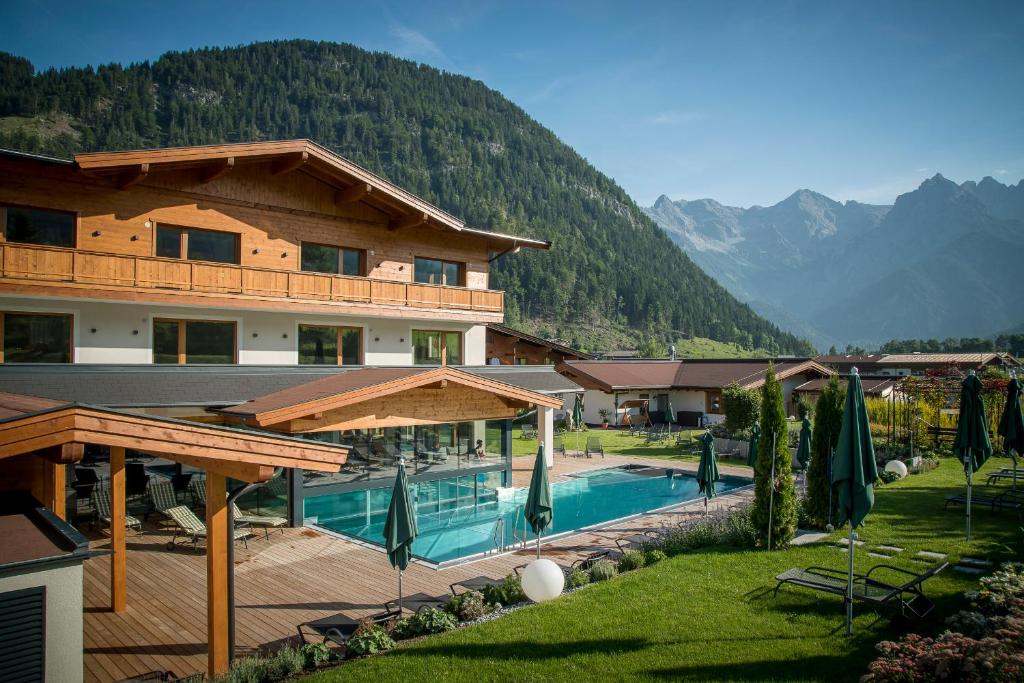 a hotel with a swimming pool in front of a mountain at Hotel Kitzspitz in Sankt Jakob in Haus