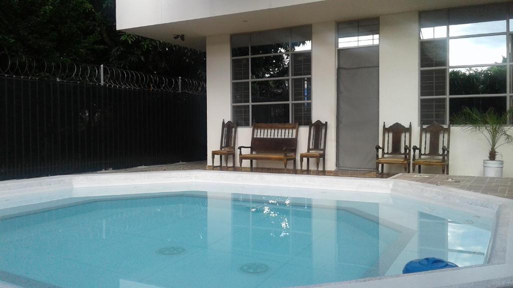 a swimming pool in a yard with two chairs at El Algarrobo in Tocaima