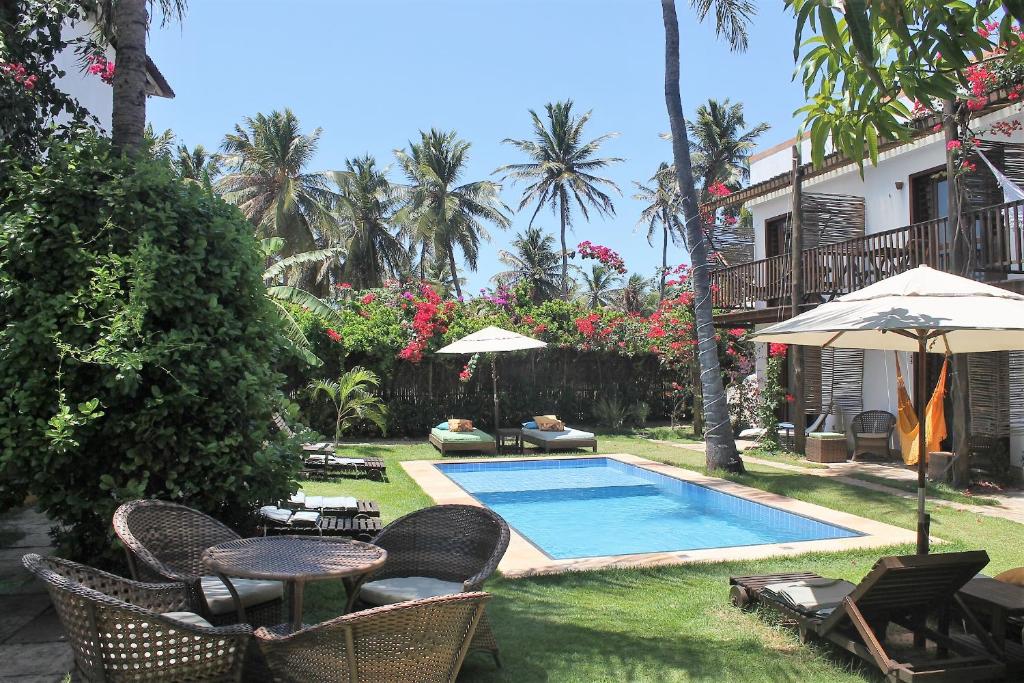 un patio trasero con piscina, sillas y sombrilla en Villa Albergaria, en Flecheiras