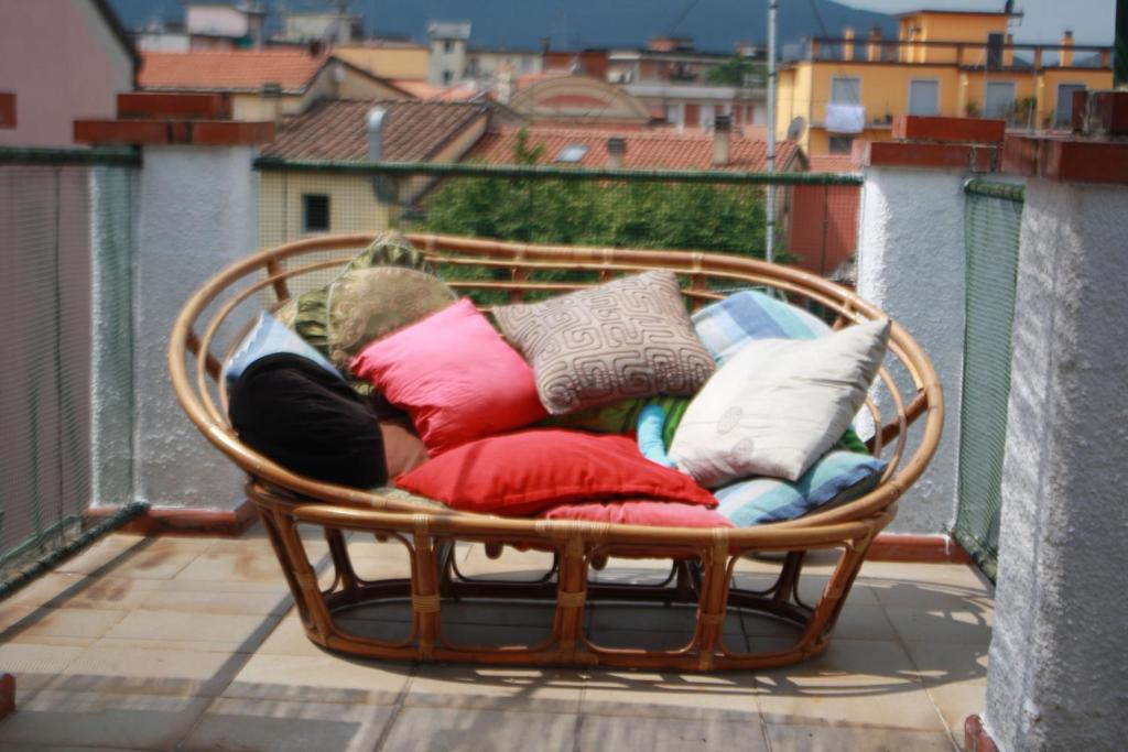 a wicker chair filled with pillows on a balcony at La Casa Torre di Eva in Sarzana