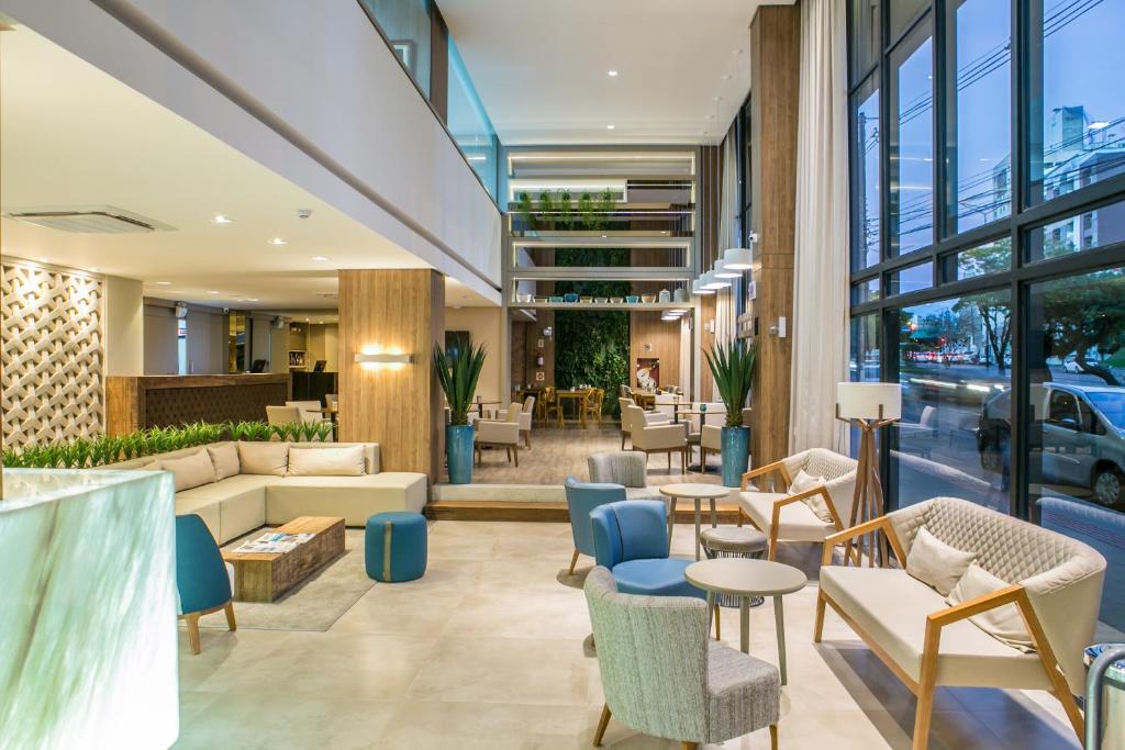 a lobby of a building with chairs and tables at Tri Hotel Premium Criciúma in Criciúma