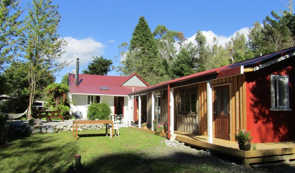 a red and white house with a yard at Greenstone Retreat in Kumara
