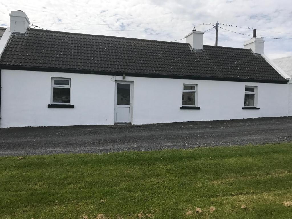 a white house with a black roof at High Road Cottage in Achill