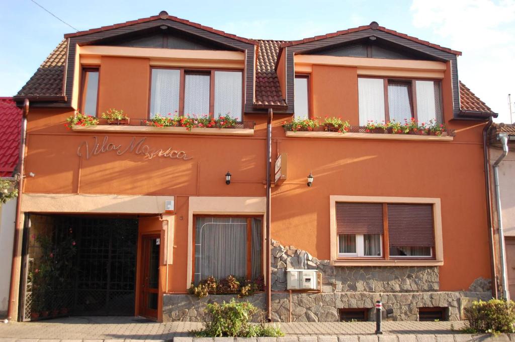 an orange house with flower boxes on the windows at Vila Monica in Târgu-Mureş