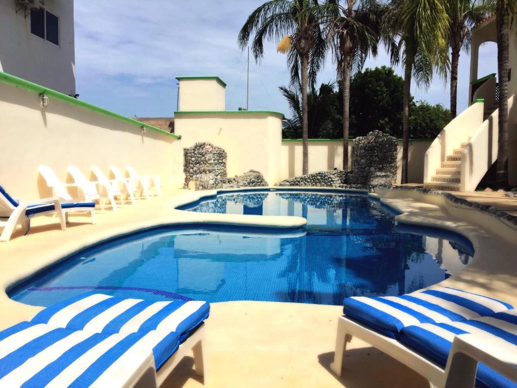 uma piscina com duas espreguiçadeiras e uma piscina em Villas Coco Resort - All Suites em Isla Mujeres