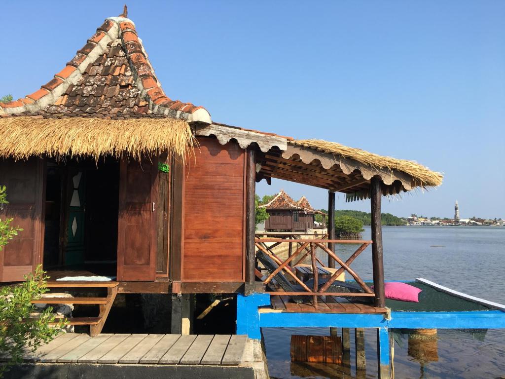 a small house on the water with a dock at Omah Alchy Cottages in Karimunjawa