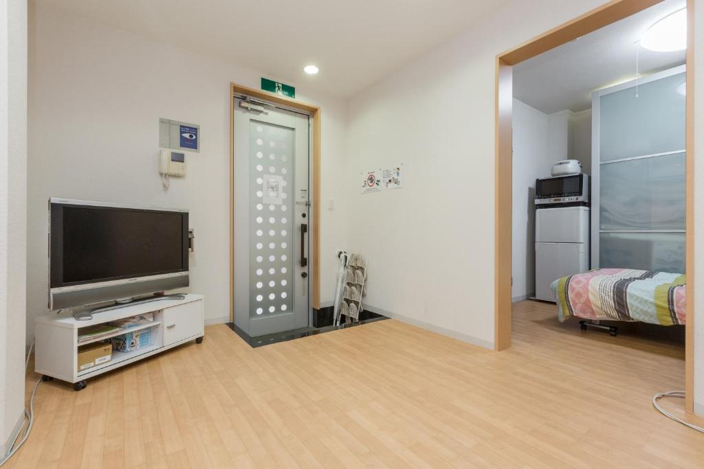 a room with a flat screen tv and a bedroom at Awaza House 1 in Osaka