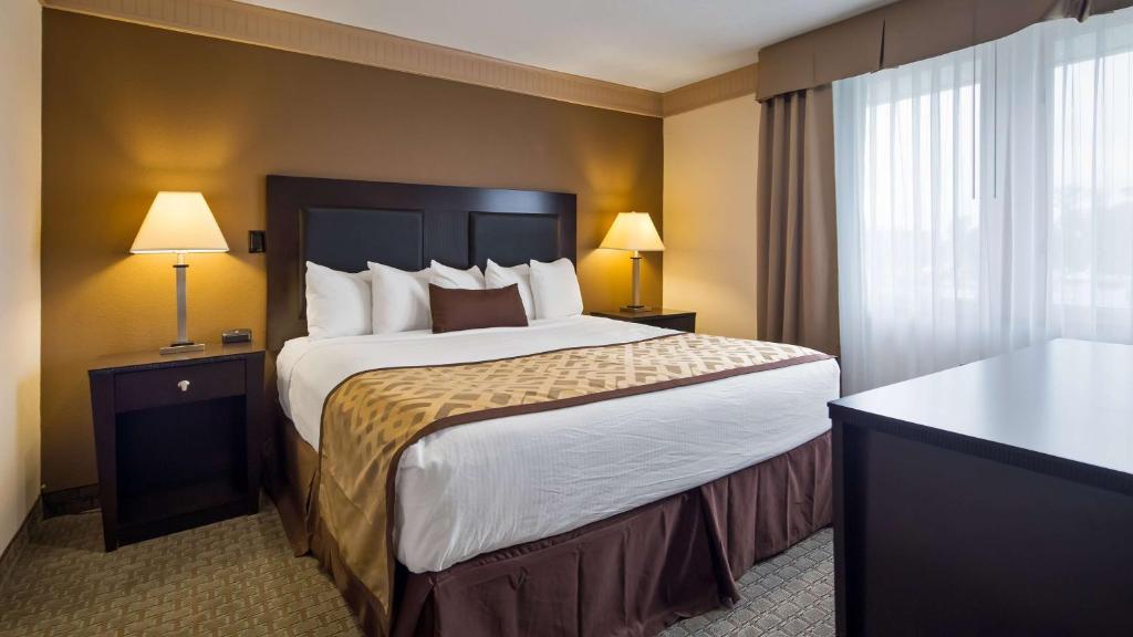 a hotel room with a large bed and two lamps at Best Western Plus Concordville Hotel in Concordville