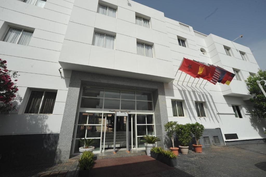 Un bâtiment blanc avec des drapeaux devant lui dans l'établissement Casablanca Suites & Spa, à Casablanca