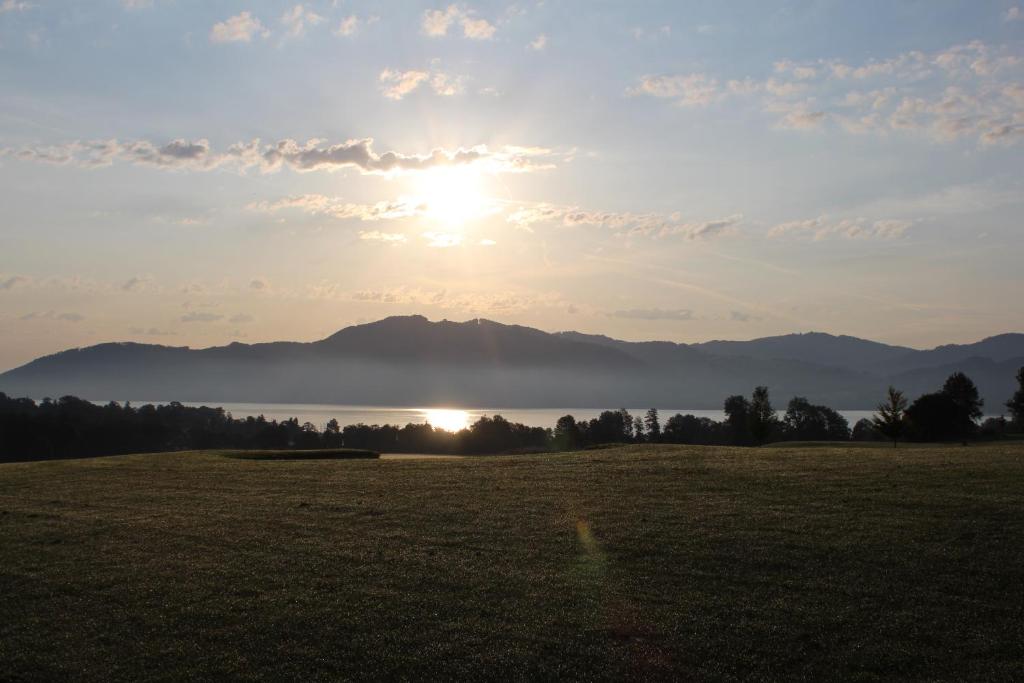 un campo con el sol saliendo sobre una montaña en Ferienwohnung Seiringer en Attersee am Attersee