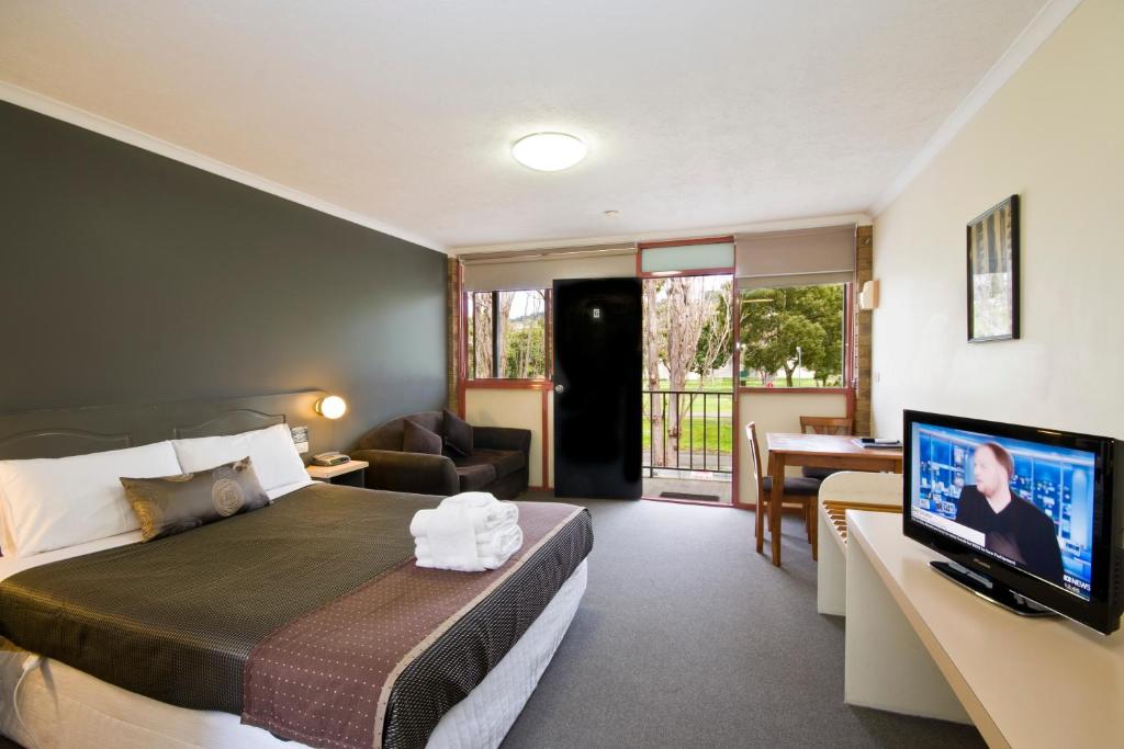 um quarto com uma cama e uma televisão de ecrã plano em Lorne Coachman Inn em Lorne