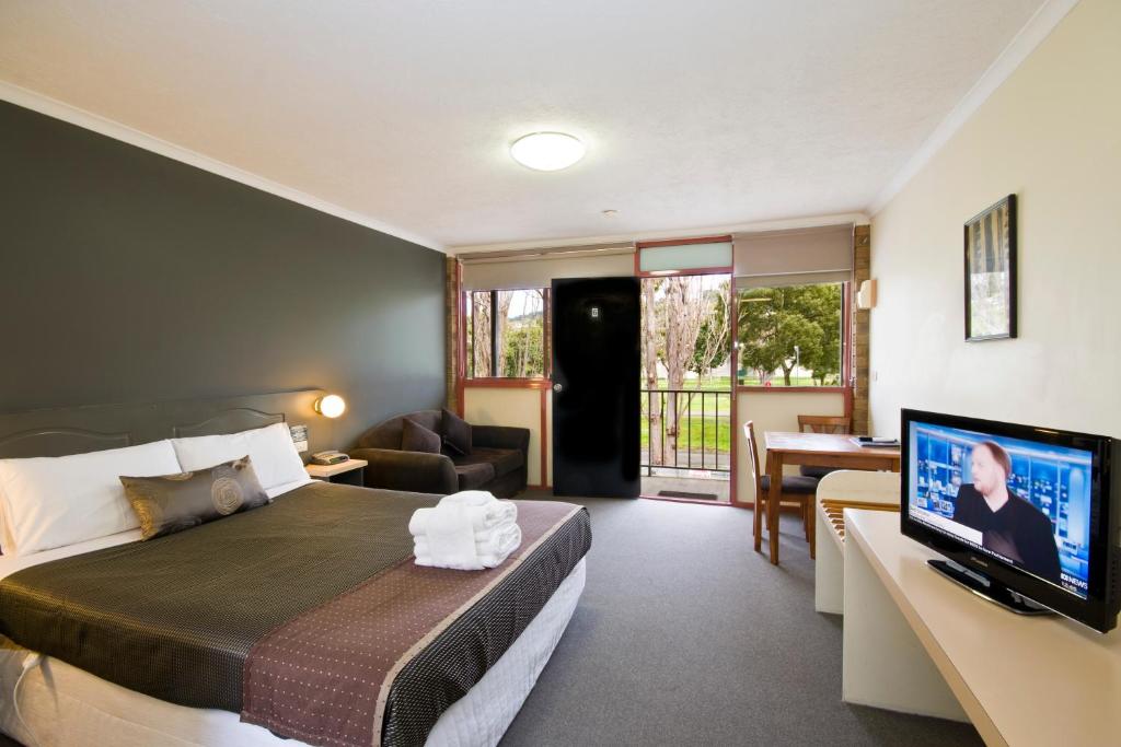 a hotel room with a bed, tv and a desk at Lorne Coachman Inn in Lorne