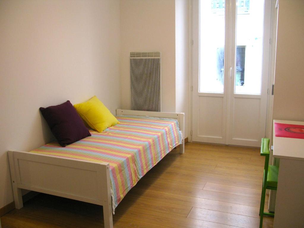 1 dormitorio con 1 cama con almohadas amarillas y moradas en Place Wilson, en Niza