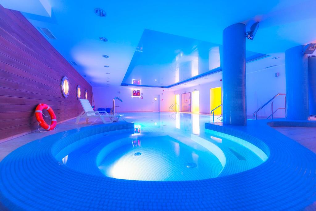 a swimming pool with a hot tub in a room at Mona Lisa Wellness & Spa in Kołobrzeg