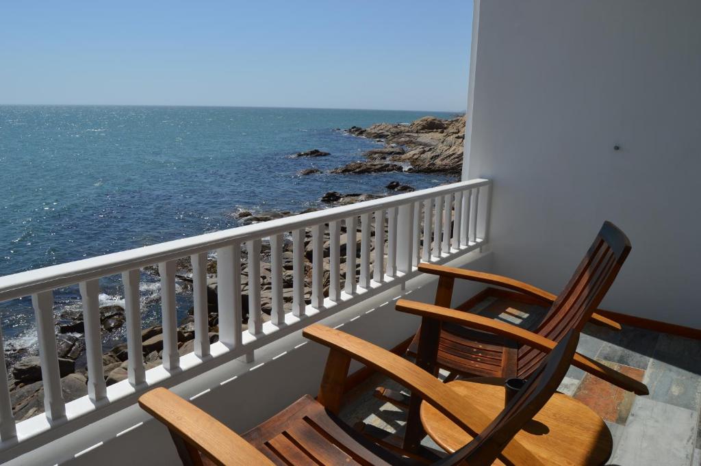 two chairs sitting on a balcony overlooking the ocean at The Cormorant House in Lüderitz