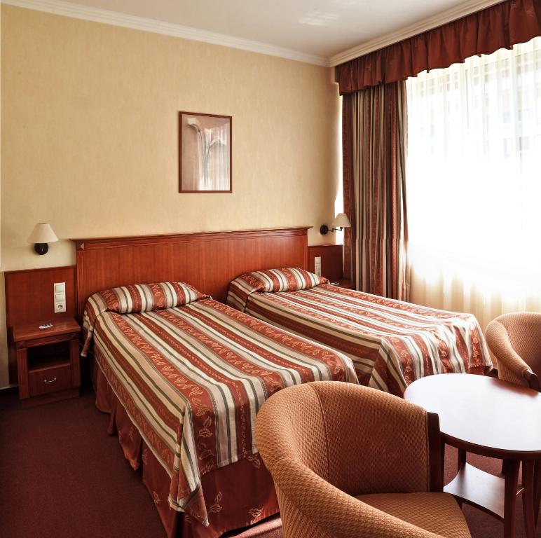 a hotel room with two beds and a table at Hotel Central in Pécs