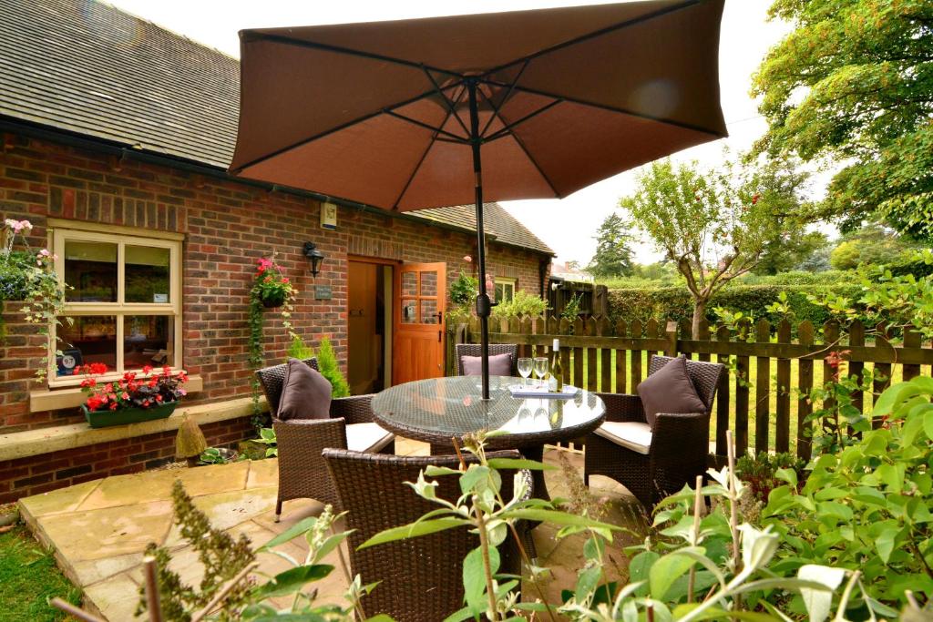 a patio with a table and chairs and an umbrella at Pine Tree Lodge, Bridgnorth in Bridgnorth