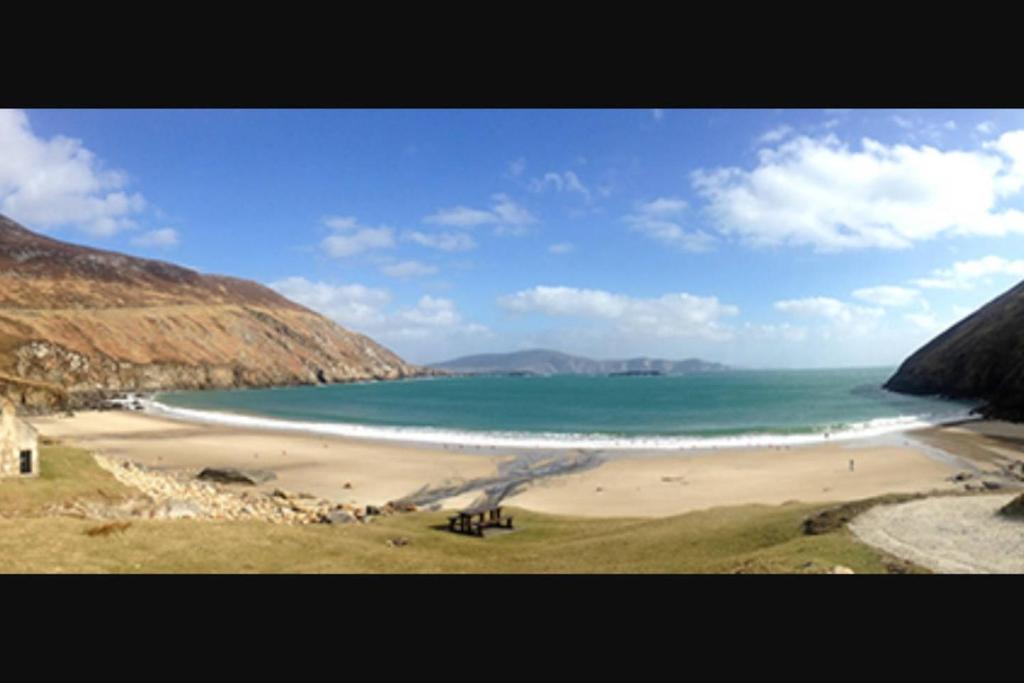 a beach with a group of people on the sand at High Road Cottage in Achill
