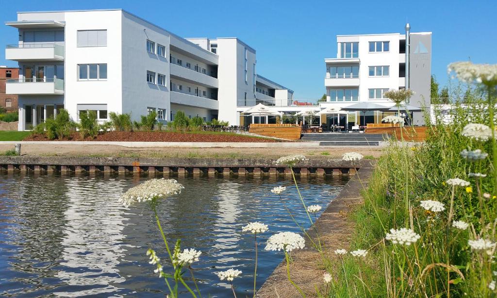 ein Fluss vor einigen Gebäuden mit Blumen in der Unterkunft PRIMA Inn Ferienwohnungen Seetor Residenz in Neuruppin