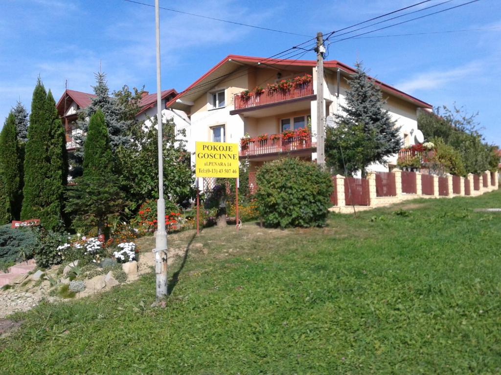 a house with a yellow sign in front of it at Pokoje Gościnne Szuber in Iwonicz-Zdrój