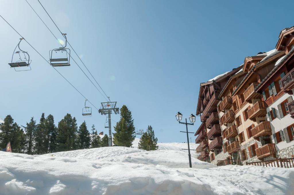 a ski lift in the snow next to a building at Résidence Pierre & Vacances Premium Arc 1950 Le Village in Arc 1950