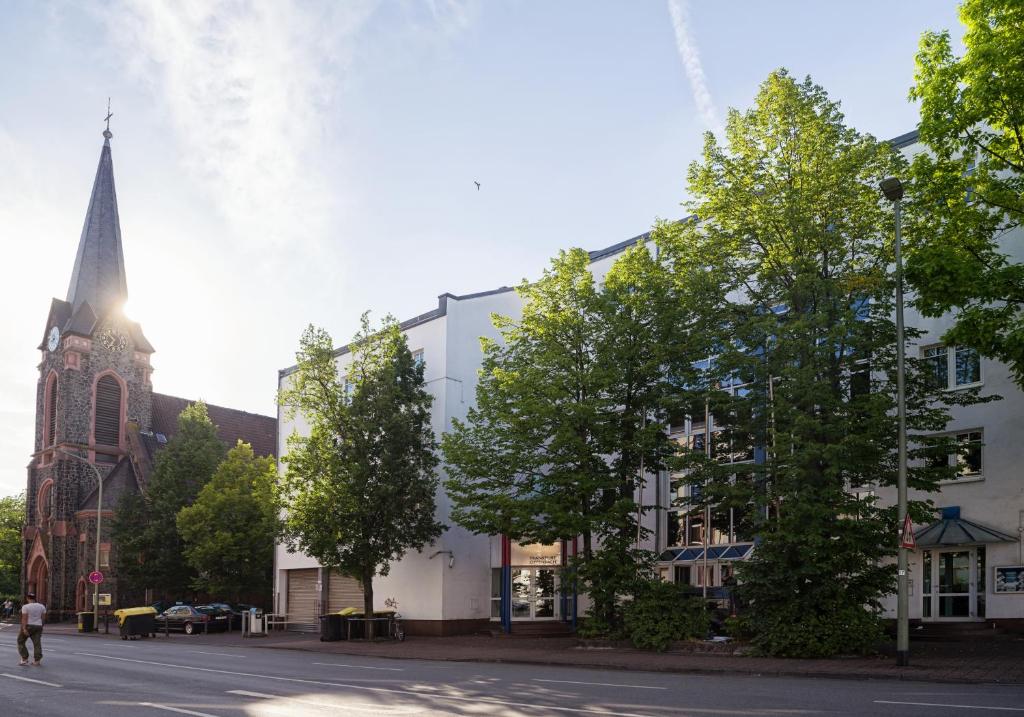 a church with a steeple and a street with trees at Hotel B99 in Offenbach