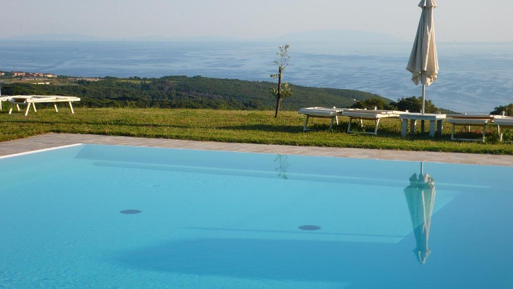 a blue swimming pool with a view of the ocean at Agriturismo San Quirico in Castiglioncello