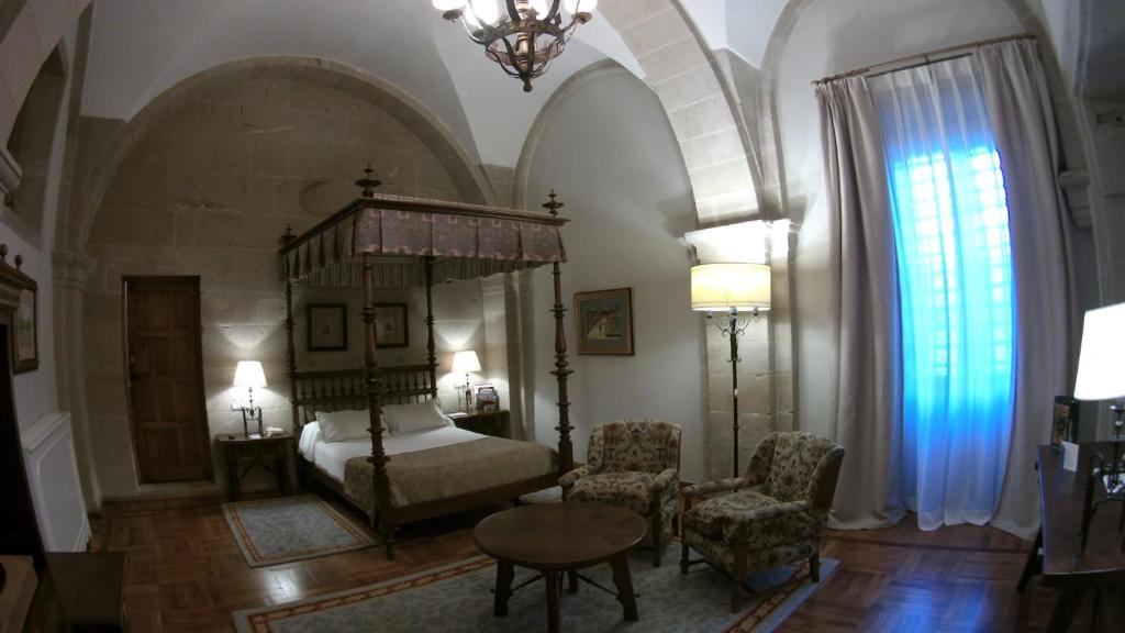 a bedroom with a bed and a table and chairs at Parador de Santiago - Hostal Reis Catolicos in Santiago de Compostela