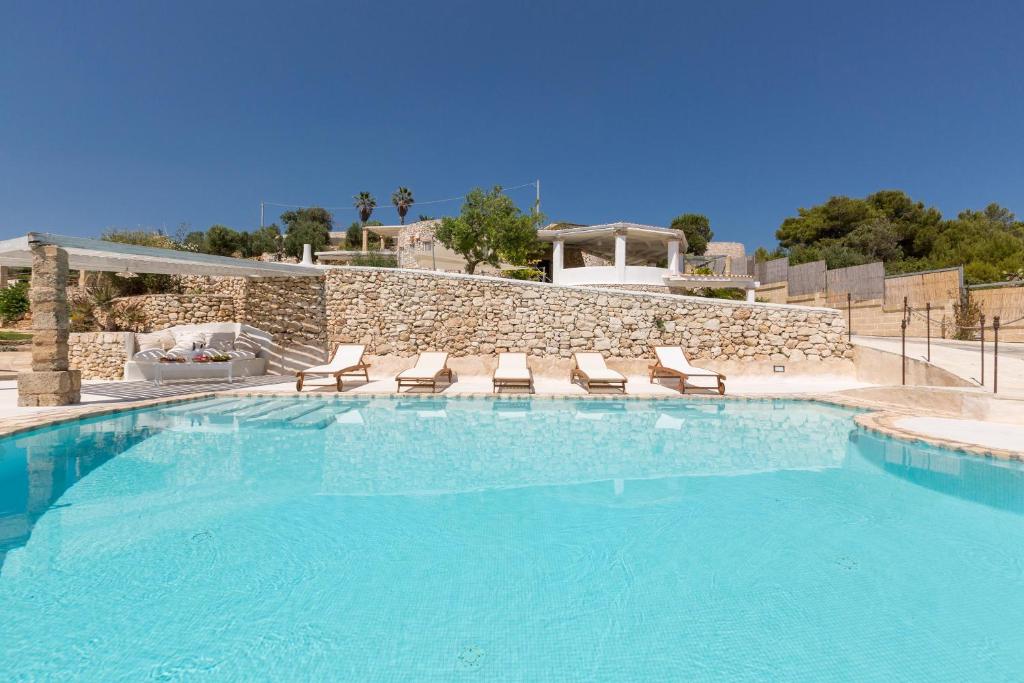 una piscina con sedie e un muro in pietra di Villa Valeria by BarbarHouse a Torre Vado