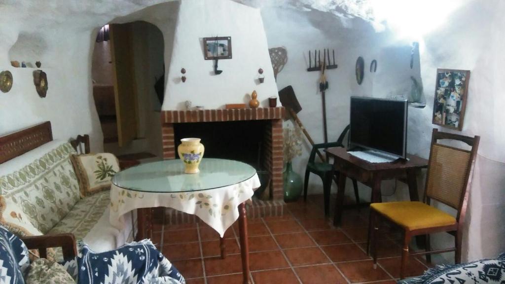 ein Wohnzimmer mit einem Tisch und einem Kamin in der Unterkunft Cueva Rural La Noguera in Pegalajar