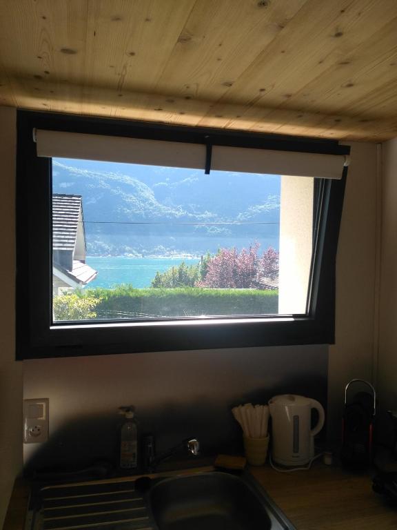 een raam boven een gootsteen met uitzicht op het water bij Le chalet du Lac in Doussard