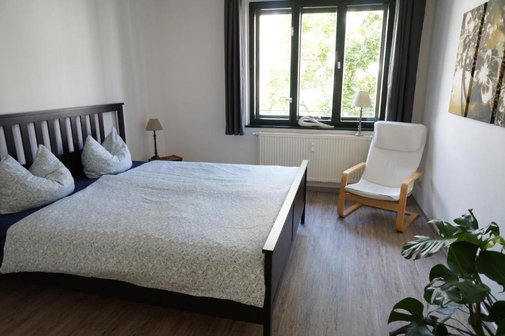 een slaapkamer met een bed, een stoel en een raam bij bluming inn - Ferienwohnung im Spreewald in Lübben