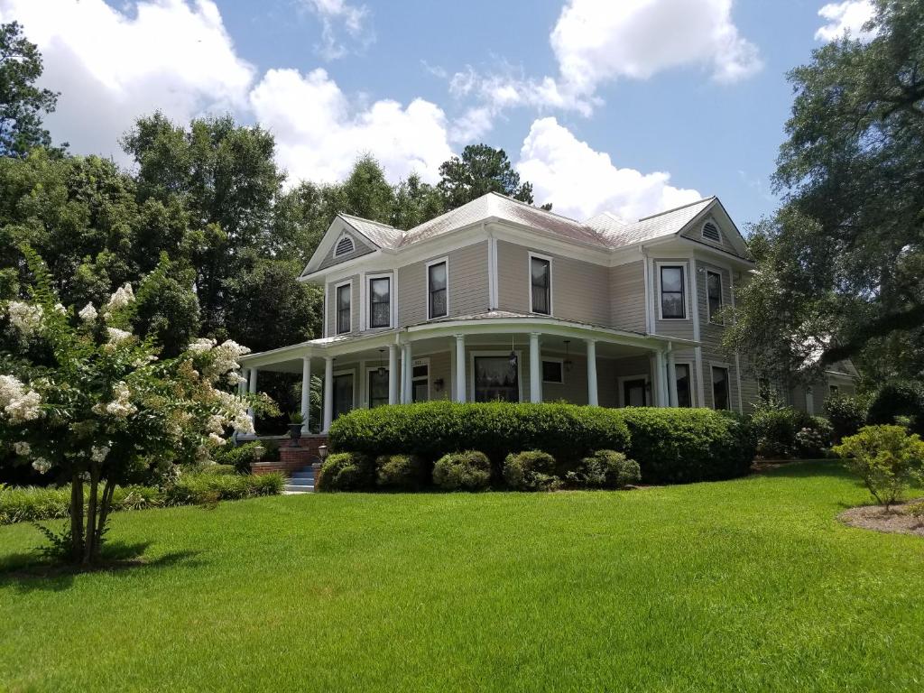 een wit huis met een groene tuin bij Thomasville Bed and Breakfast in Thomasville