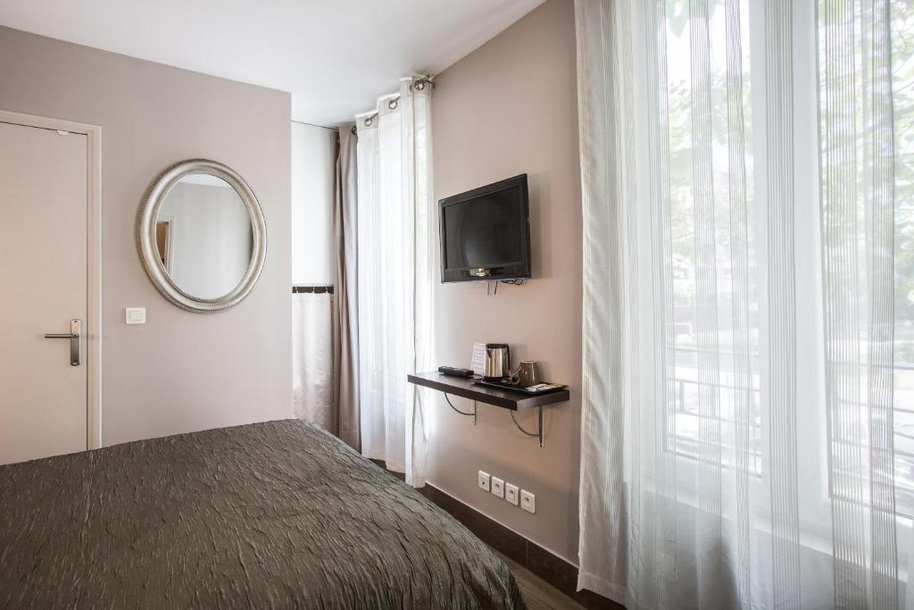 a bedroom with a bed and a mirror and a window at Le Figuier in Ivry-sur-Seine